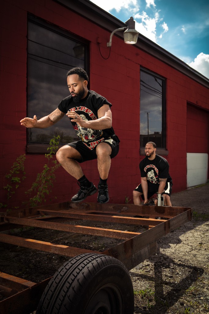 Athlete in GRODT tee and shorts box jumping onto a steel trailer frame